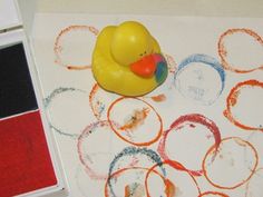 a rubber ducky toy sitting on top of a table next to some colored crayons