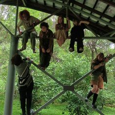 several people are hanging upside down in the air on a metal structure with trees and bushes behind them