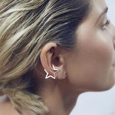 a woman wearing two star shaped earrings on her ear