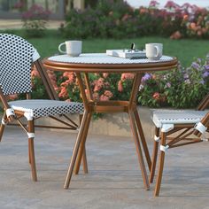 two chairs and a table outside with flowers in the background