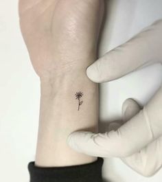 a woman's wrist with a small tattoo of a dandelion on it