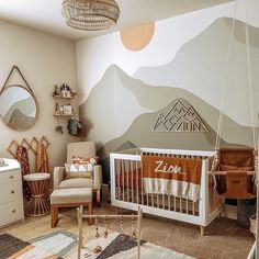 a baby's room with mountains painted on the wall and crib in the corner