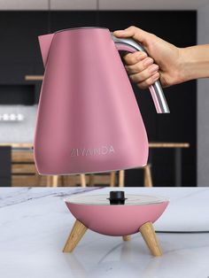 a person is pouring liquid into a pink kettle