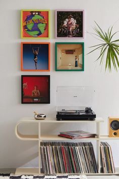 a record player sitting on top of a table next to a wall mounted with records