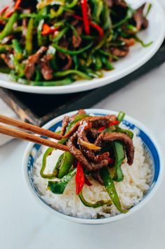 two plates filled with stir fry beef and veggies on top of white rice