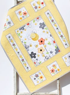 a yellow and white quilted square with flowers on it sitting in front of an old window