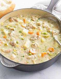 a pot filled with chicken and dumpling soup next to a piece of bread on a table