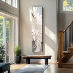 a living room filled with furniture and lots of windows next to a stair case in front of a painting on the wall