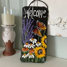 a welcome sign sitting on top of a counter next to a candle holder and vase