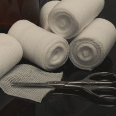 some white towels and scissors on a black table with brown bottles in the back ground