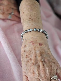 an older woman's arm with a bracelet on it and some beads around the wrist