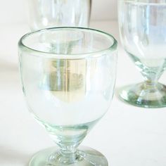 three glass goblets sitting next to each other on a white counter top,