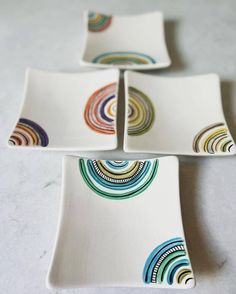 four square plates with colorful designs on them