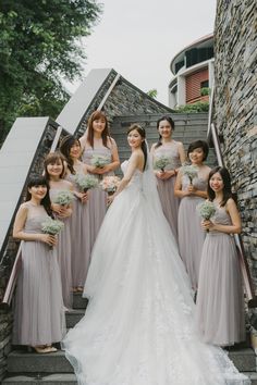 a group of women standing next to each other in front of a stone wall and stairs