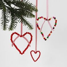 three ornaments hanging from a christmas tree with beaded hearts and beads attached to them