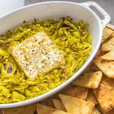 a white bowl filled with food next to crackers