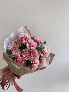 a bouquet of pink carnations wrapped in brown paper