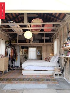 a bed sitting inside of a wooden room next to a closet filled with books and other items