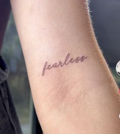 a person with a tattoo on their arm that says fearless in cursive writing