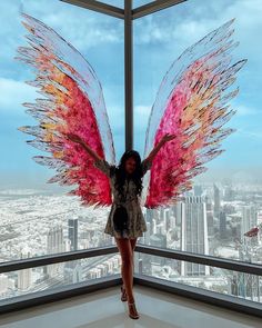 a woman standing in front of a window with wings