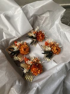 four hair combs with flowers and spikes on top of white tissue paper in a box