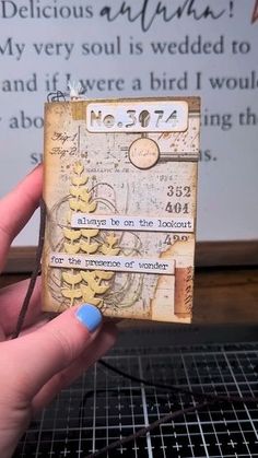 a person holding up a small piece of paper that has been altered to look like an old book