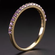 a yellow gold ring with purple stones on the inside and outside, set against a black background