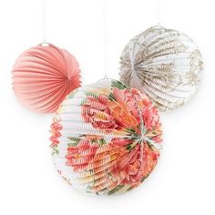 three paper lanterns hanging from strings on a white wall, each with an ornament in the shape of a flower