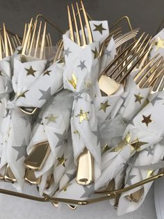 gold and white forks and napkins are arranged in a star - patterned basket on a table