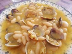 a bowl filled with lots of clams and white beans on top of a table