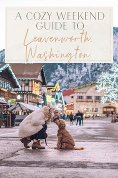 a woman kneeling down next to a dog in front of a sign that reads a cozy weekend guide to leaveworth, washington