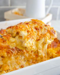 a spoon full of cheesy casserole being lifted from a white dish