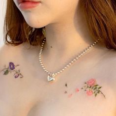 a close up of a woman's chest with flowers on it and a heart shaped pendant