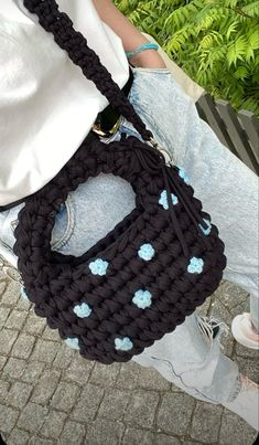 a woman is holding a black purse with blue flowers on the front and bottom part