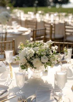 the table is set with white flowers and silverware