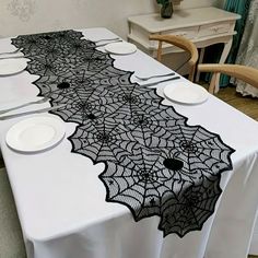 an image of a table setting with white plates and black lace on the table runner