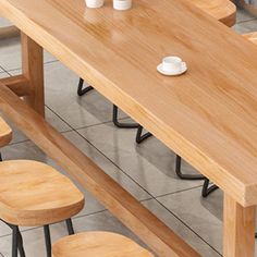 a wooden table with four stools and two cups on it, in the middle of a tiled floor