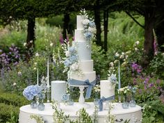 a wedding cake sitting on top of a white table surrounded by flowers and greenery