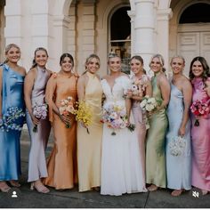 a group of women standing next to each other in front of a building with flowers