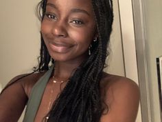 a woman with long braids is smiling at the camera while wearing a green tank top