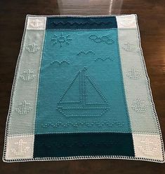 a blue and white crocheted blanket on top of a wooden table