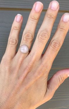 A beautiful round pink rose quartz sits in sterling silver with a handmade ring band from sterling silver half dome wire. Choose from either a simple setting or a more floral scallop setting. The rose quartz cabochon is 11mm in size. Rose quartz is a stone that promotes healing, love, and attraction. It can draw love to the the wearer, help heal from heartbreak, and help sustain feelings of love and romance. Made to order, stones vary with slight differences in color, lines, etc. Blush Gemstone Rings As Gift, Blush Gemstone Rings For Gifts, Delicate Adjustable Stackable Rings, Minimalist Pink Crystal Ring As Gift, Minimalist Round Cabochon Jewelry, Adjustable Sterling Silver Pearl Ring For Everyday, Delicate Pink Sterling Silver Rings, Pink Sterling Silver Moonstone Promise Ring, Pink Sterling Silver Crystal Ring