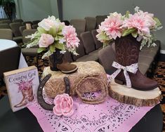 cowboy boots and flowers are sitting on a pink table cloth next to a cowgirl's boot