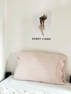 a white bed topped with pink pillows next to a wall mounted photo on the wall