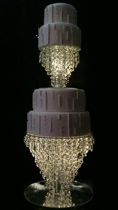 a three tiered cake sitting on top of a glass plate covered in icing