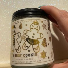 a hand holding a jar of merry cookie scented candle