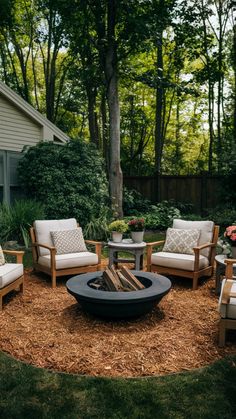 an outdoor fire pit surrounded by chairs and tables in front of a house with trees