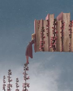 a woman standing on top of a tall wooden structure with flowers growing out of it