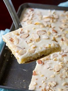 a piece of cake with white frosting and nuts on top is being held by a fork