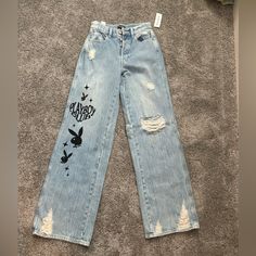 Wide Legged Light Blue Playboy Jeans From Pacsun. Multiple Buttons And Very Comfy And Cute. Size 24 With Tags Still On. Never Worn. Trendy Spring Jeans With Graphic Print, Spring Graphic Print Denim Pants, Casual Graphic Print Bottoms For Day Out, Graphic Print Bottoms For Day Out In Spring, Graphic Print Bottoms For Day Out And Spring, Spring Graphic Print Bottoms For Day Out, Trendy Blue Graphic Print Bottoms, Trendy Blue Bottoms With Graphic Print, Blue Pants With Graphic Print For Spring